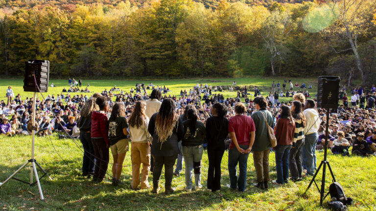 A group of students performing outdoors in a grassy field on Mountain Day