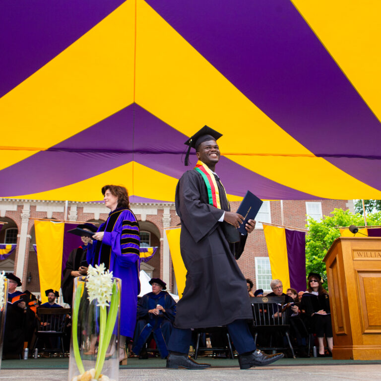 A student walking across the stage with their diploma at commencement