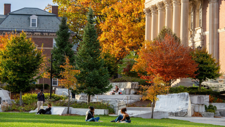 Students sitting outside and having conversations in the fall