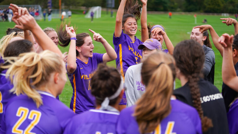 A group of players on a soccer team laughing and jumping