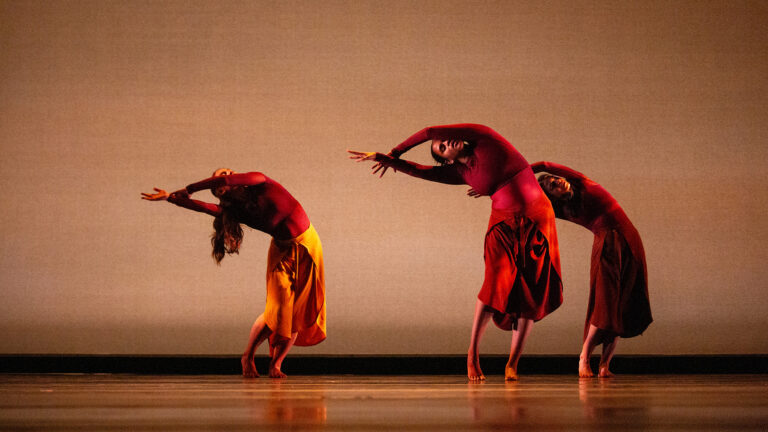 Three students dance dramatically on a stage