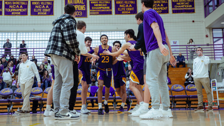 One student runs through two lines of teammates facing him and holding up hands for high fives