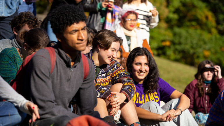 students sit outside on a hillside