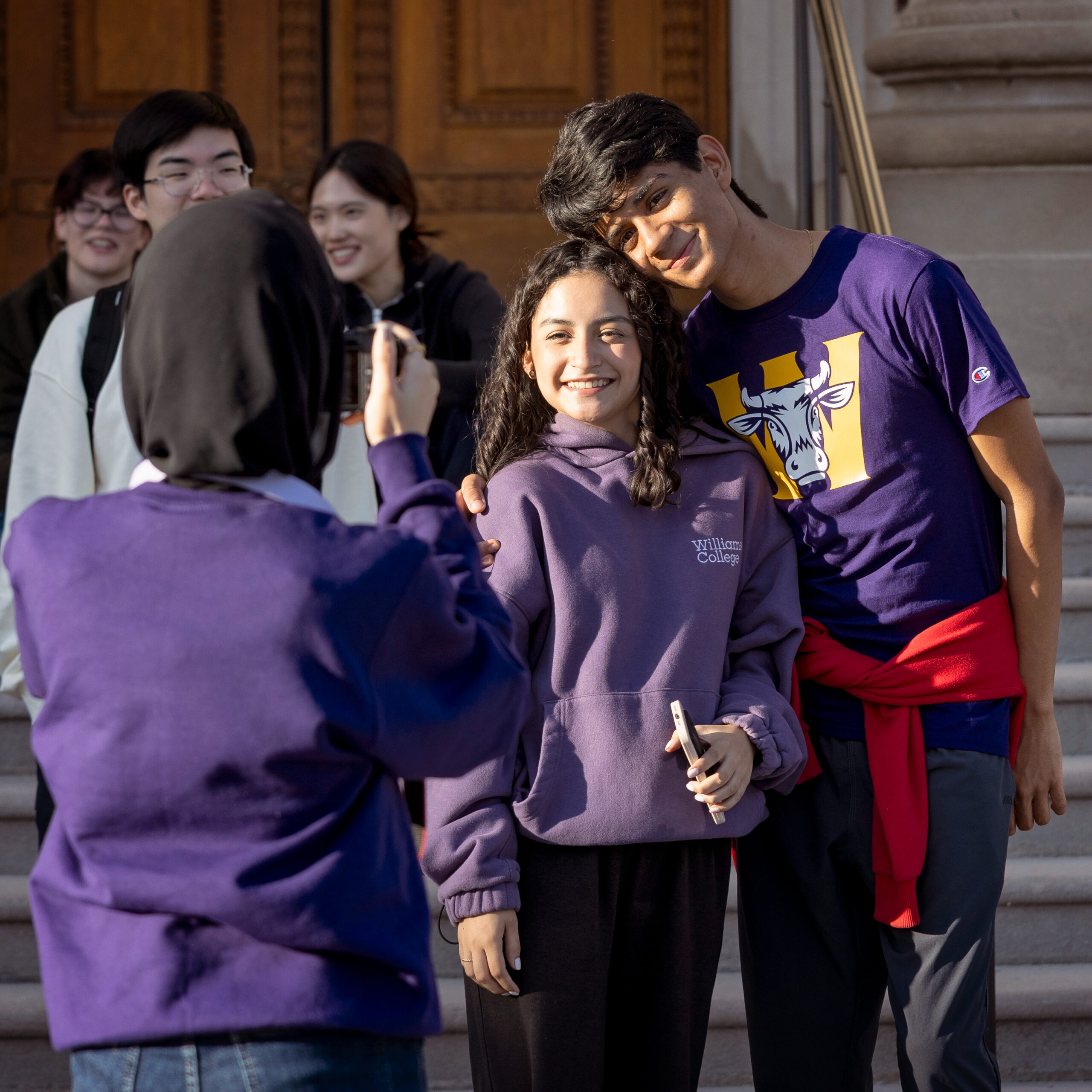 A student taking a photo of two other students posing together