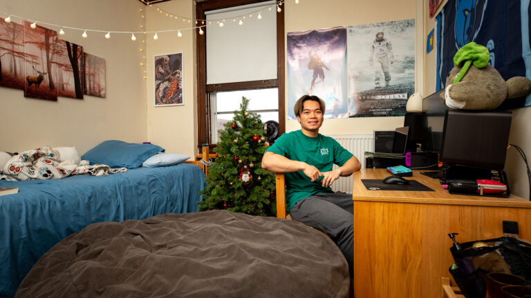 A student sits in his well-decorated dorm room