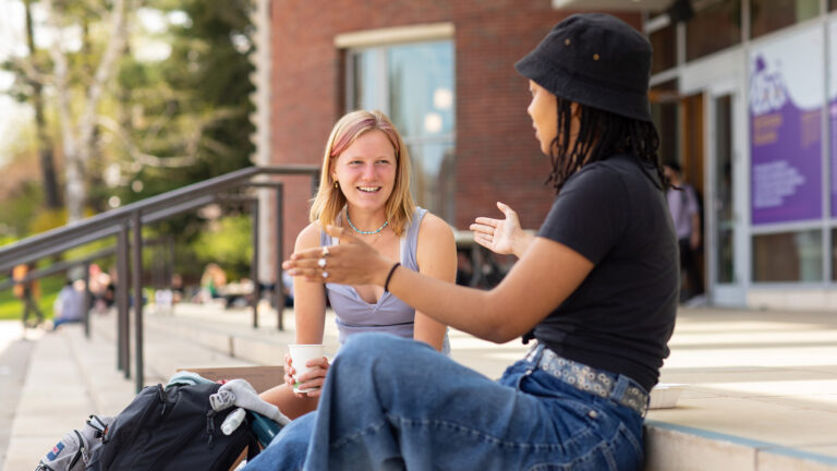Two students chat on the steps of Paresky hall