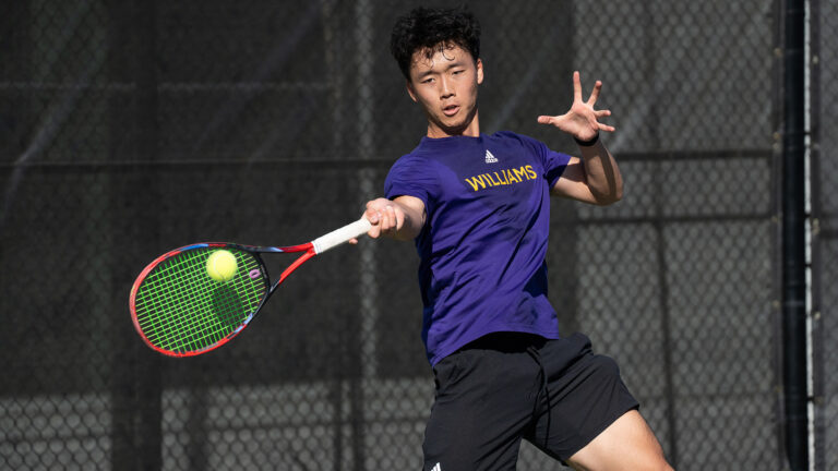 A student tennis athlete about to strike a tennis ball with their racquet