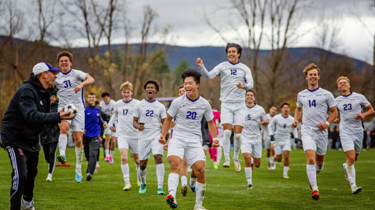 Student soccer athletes all wearing uniform and celebrating with their coach