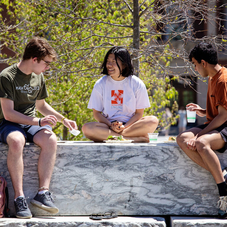 Three students sitting outdoors together on a spring day