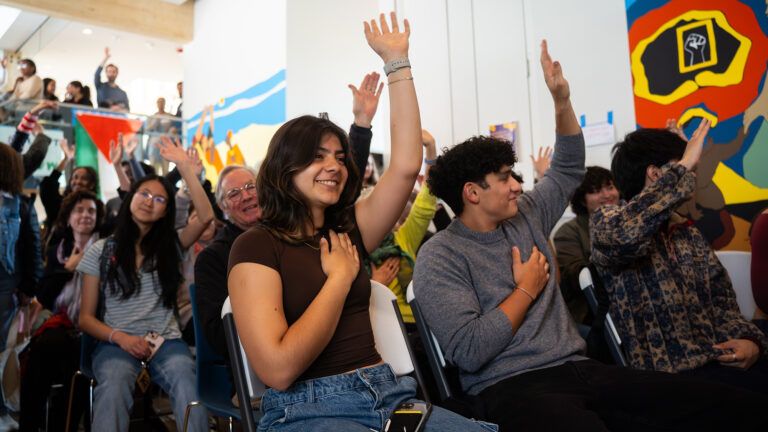 Students placing one hand on their chests and one in the air during an an event at the Davis Center