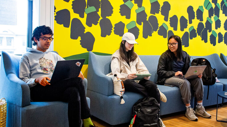 Three students sitting and working on their laptops