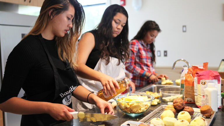 Three students cooking in a communal kitchen