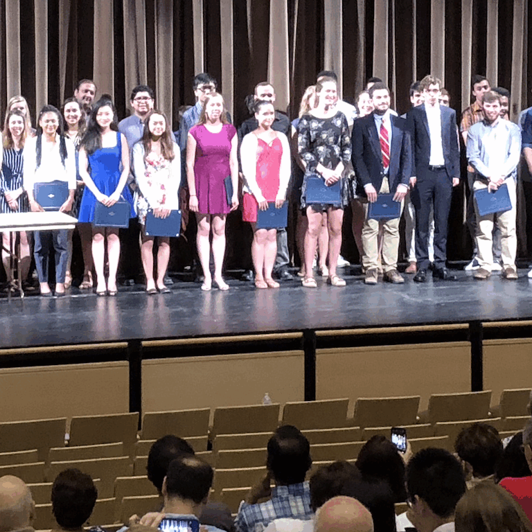A group of students and faculty standing on stage