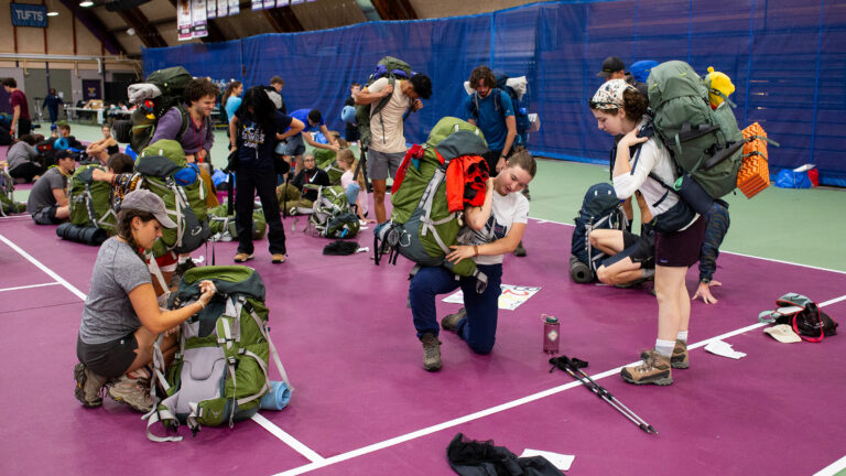 A group of students preparing large backpacks for an outing