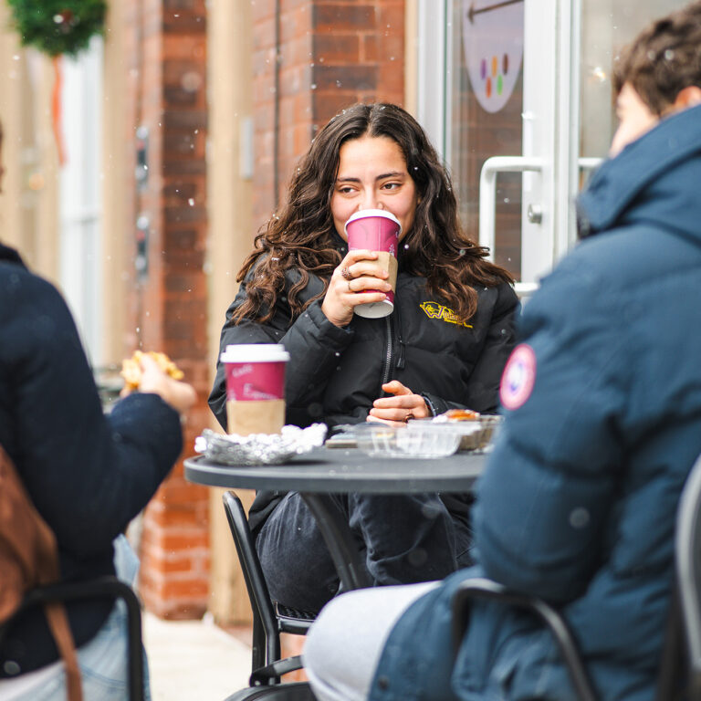 a student drinking coffee at the spring street market