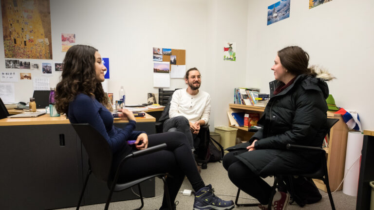 Two students meet with a teaching associate