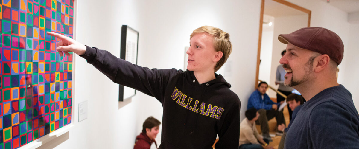 A student and professor looking at art on the wall of the Williams College Museum of Art