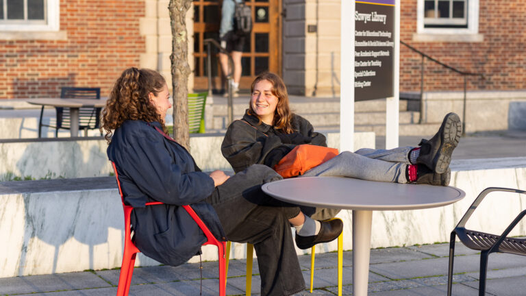 Students sitting and having a conversation outside of Sawyer Library