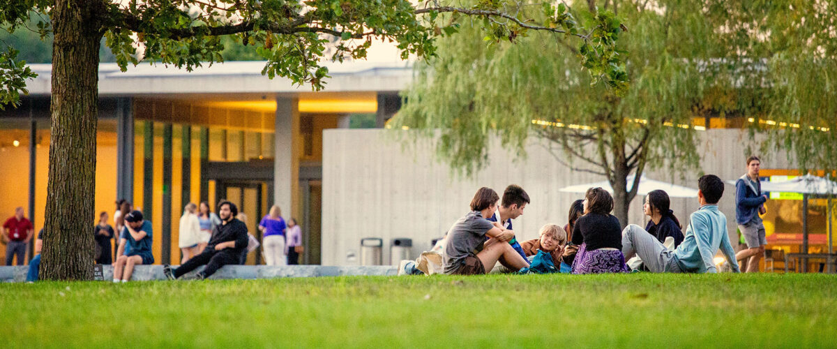 A group of students lounging on the grass together on the grounds of the Clark Art Institute