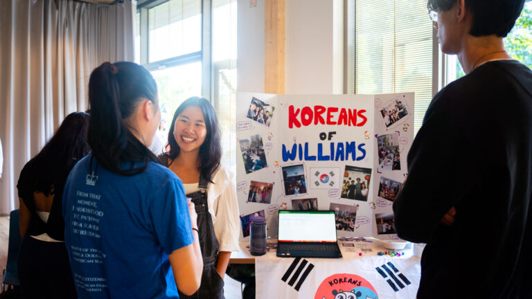 A student representing Koreans of Williams at a tabling event speaking with visitors to their table