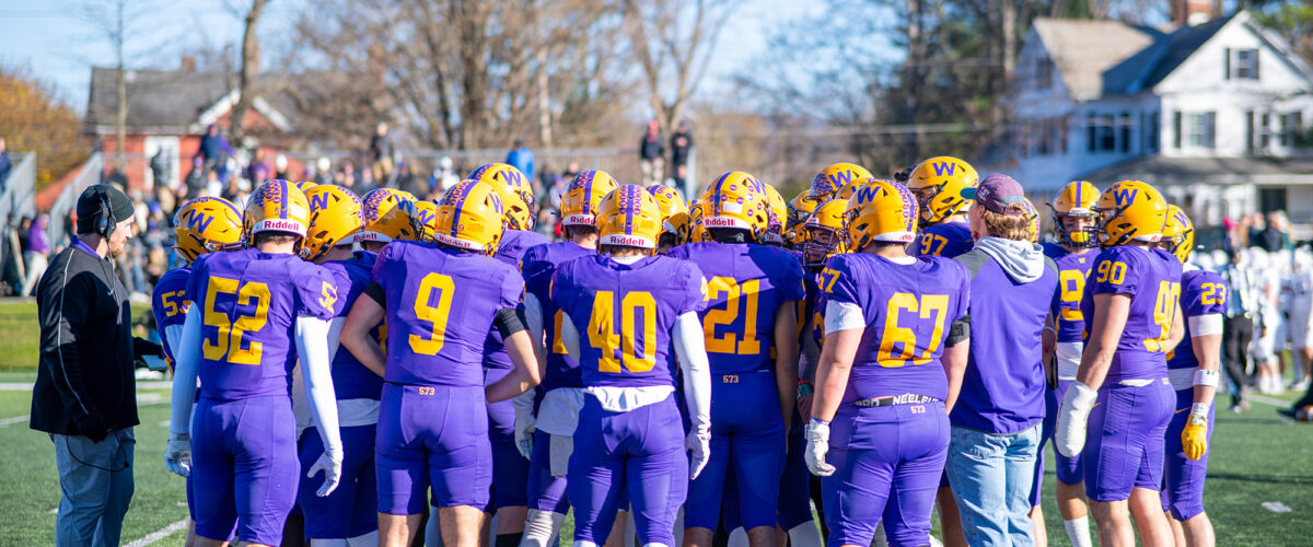 The Williams football team in a huddle during Homecoming