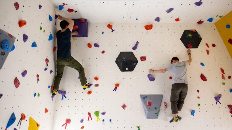 Two students at the top of a climbing wall that they have climbed up