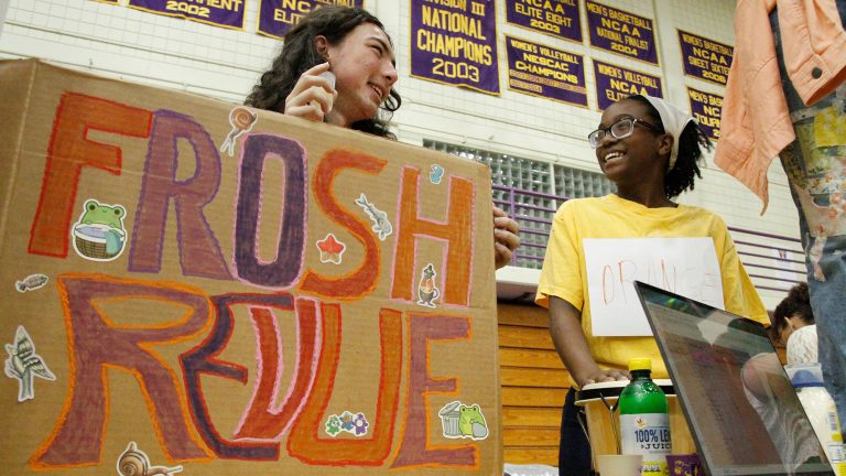 Two students talking and smiling while working at a tabling event