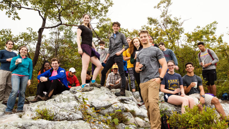 A large group of students standing on a rock after a hike