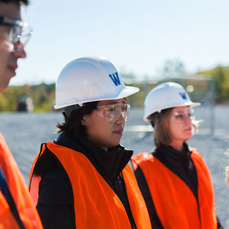 A group of students wearing high visibility vests and hardhats while visiting a transfer station