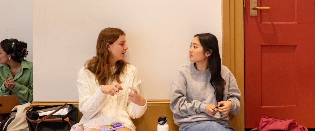 Two students sitting on the floor and talking in Goodrich Cafe