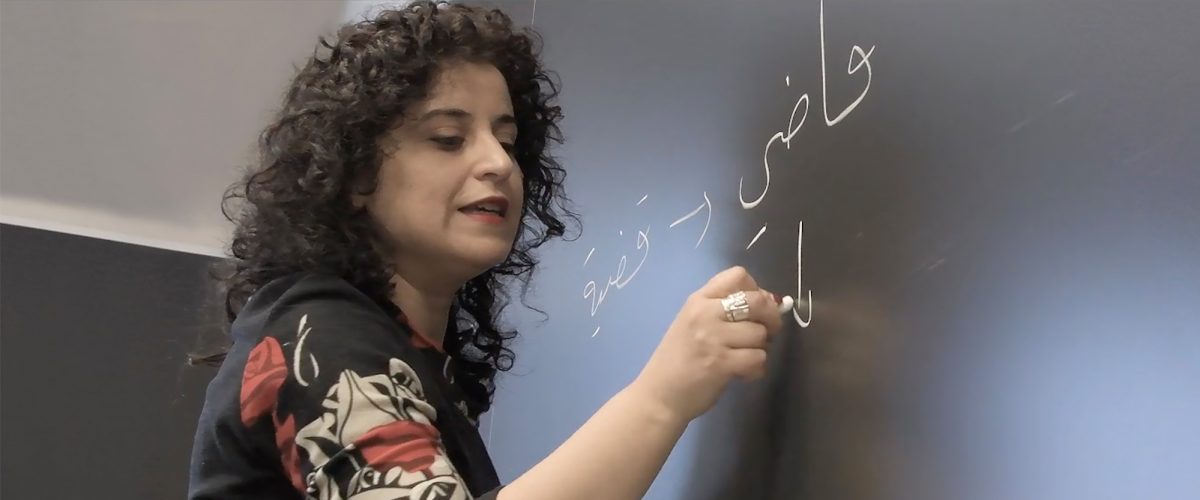 Professor writing in Arabic on a blackboard