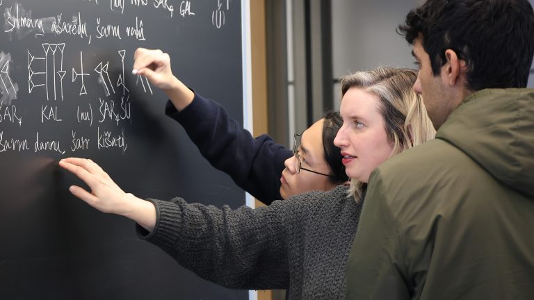 Students writing with chalk on a blackboard