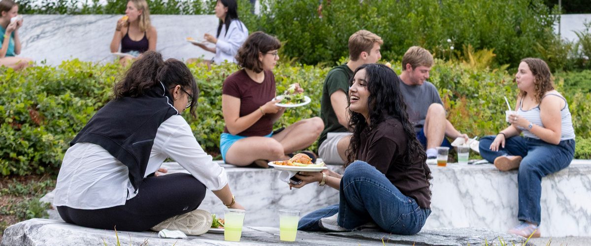 Students sit on stone benches outdoors during an all-campus picnic