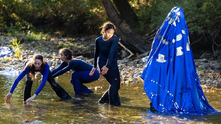Student dancers performing a piece in a riverbed.