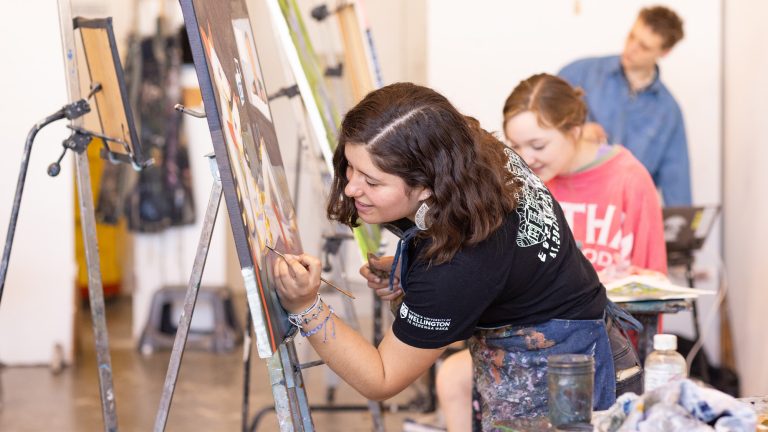 A student painting on a canvas in a studio art class