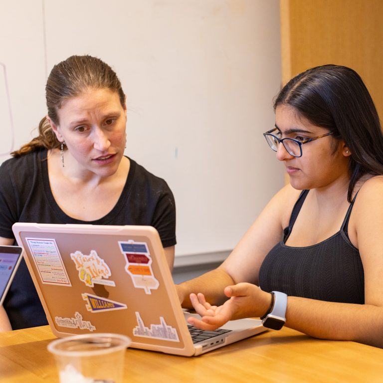 A professor and student looking at a laptop together