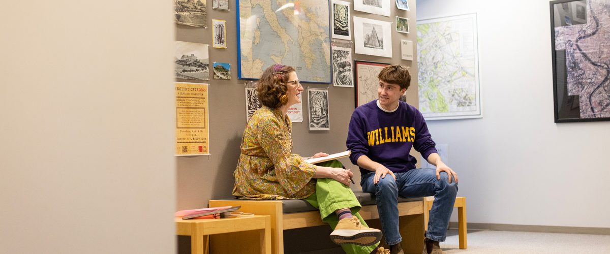 A student and a professor sit on a bench having a conversation