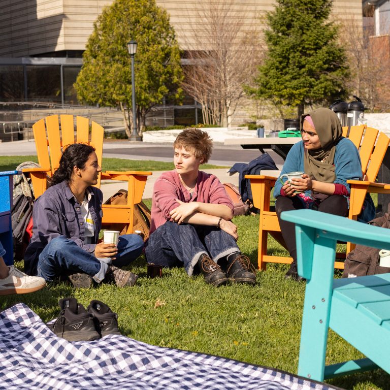 Students and a chaplain sit outside talking