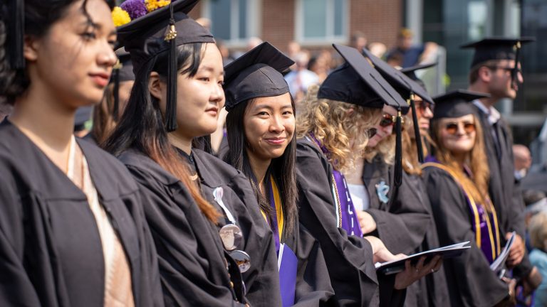 a row of seated students dressed in graduation caps and gowns at commencement