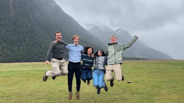 Students jumping and posing for a photo in front of foggy mountains while on Study Away