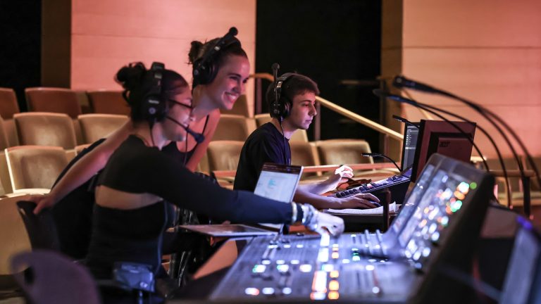 Students working behind a sound booth at a concert