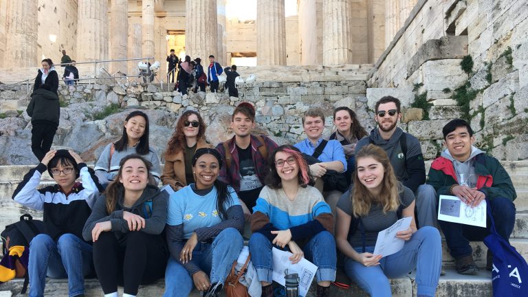 A group of Classics students posing for a photo in front of a historical ruin on a Study Abroad trip to Greece