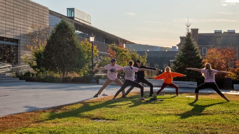 students do yoga outdoors in evening light