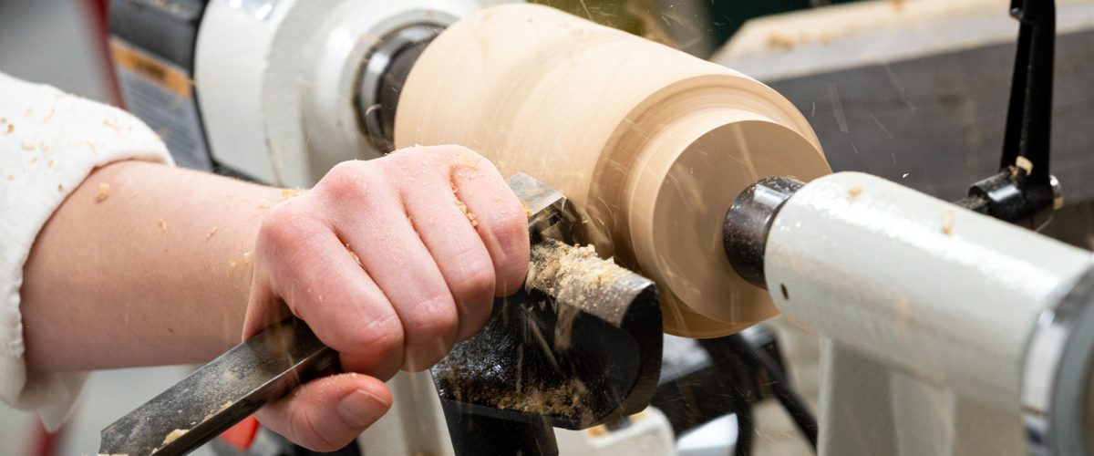 A student turns wood on a lathe