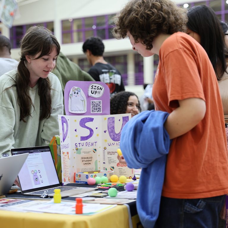 students talk by the signup table for the disabled students union