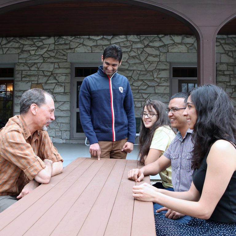 CDE students and a professor sit around a picnic table talking