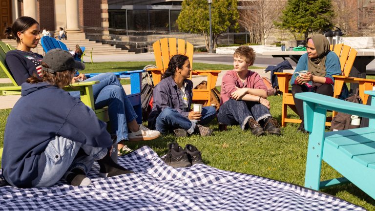 A group of students and a chaplain sitting in a circle outdoors