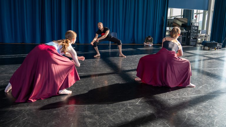 Two dance students working in the studio with a guest