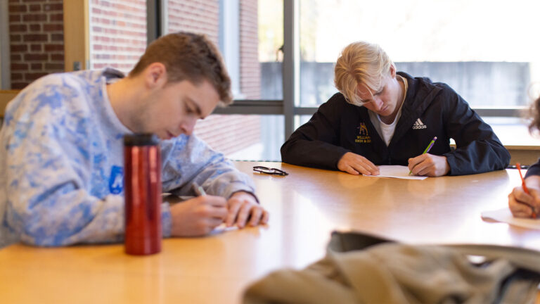 Two students taking notes in a Russian class