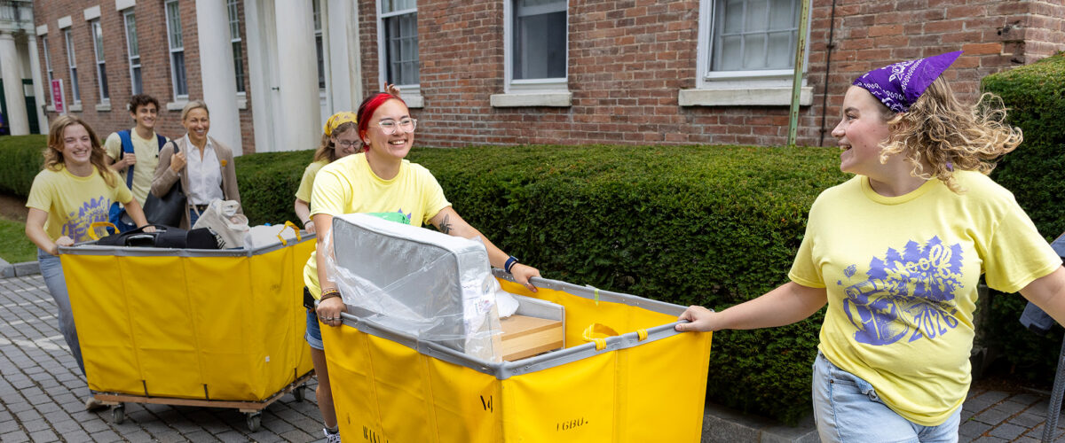 students pushing carts full of luggage